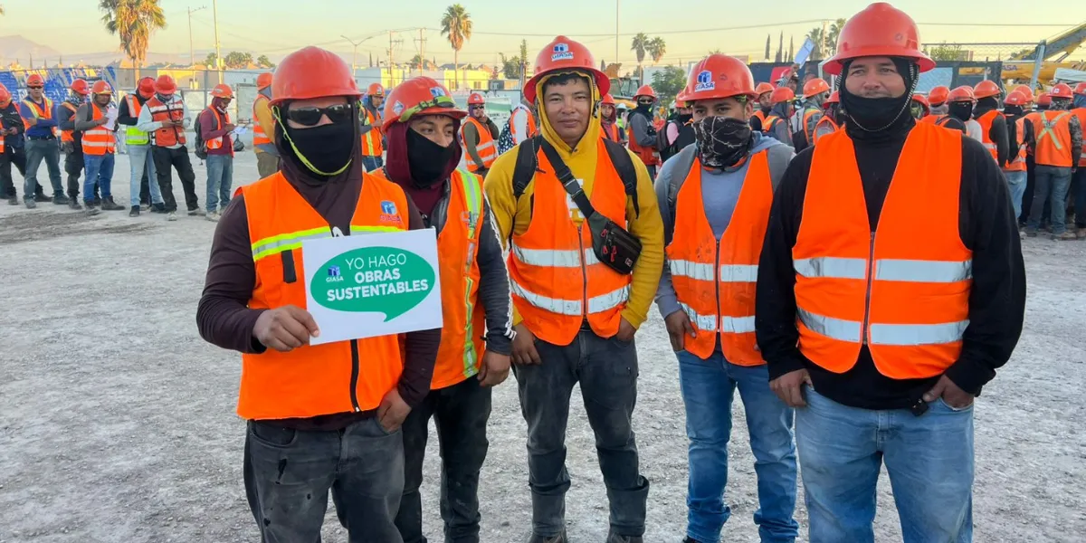 Trabajadores de GIASA en obra portando chalecos reflectantes y casco, sosteniendo nuevamente el mensaje “Yo hago obras sustentables”, durante una dinámica de cultura ambiental.